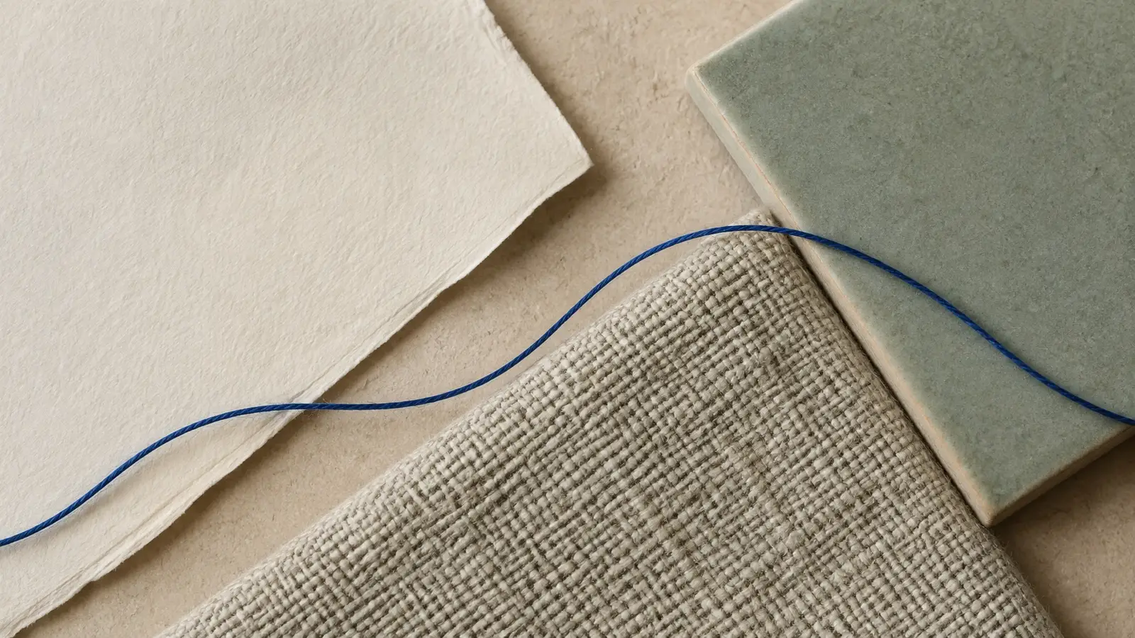 Paper, woven fabric, and ceramic joined by a thin blue thread